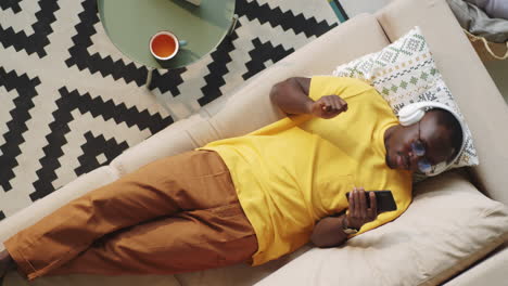 Black-Man-in-Headphones-Listening-to-Music-on-Smartphone-at-Home